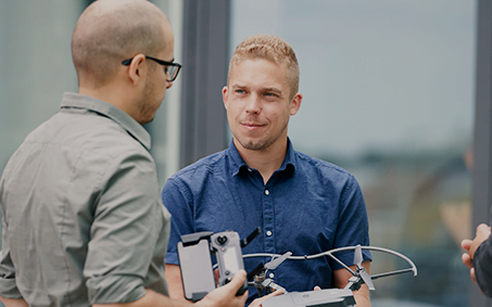 to mænd der snakker sammen mens den ene holder en drone