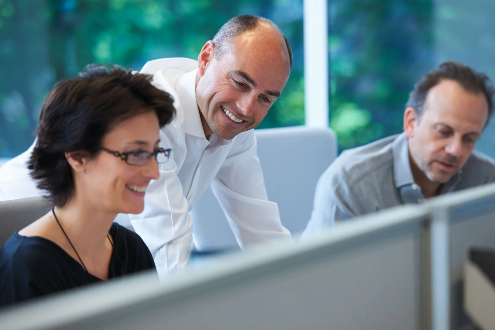 Kolleger sidder ved skrivebordet og smiler