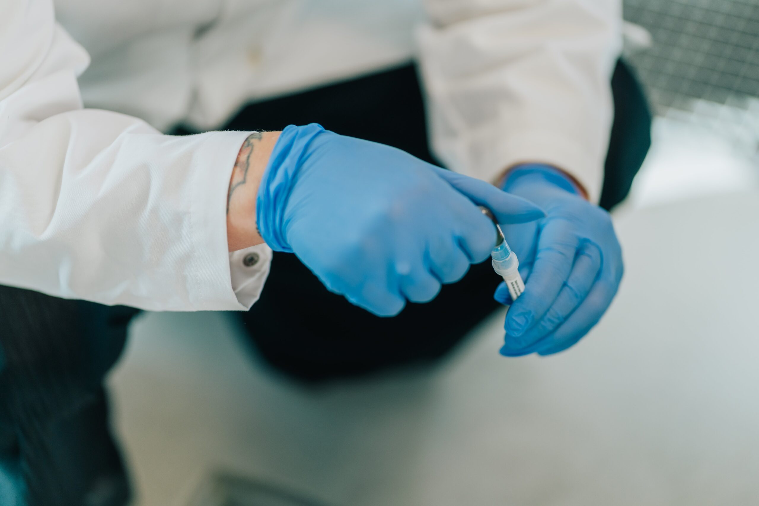 Laborant håndterer prøve med pipette i laboratorium.