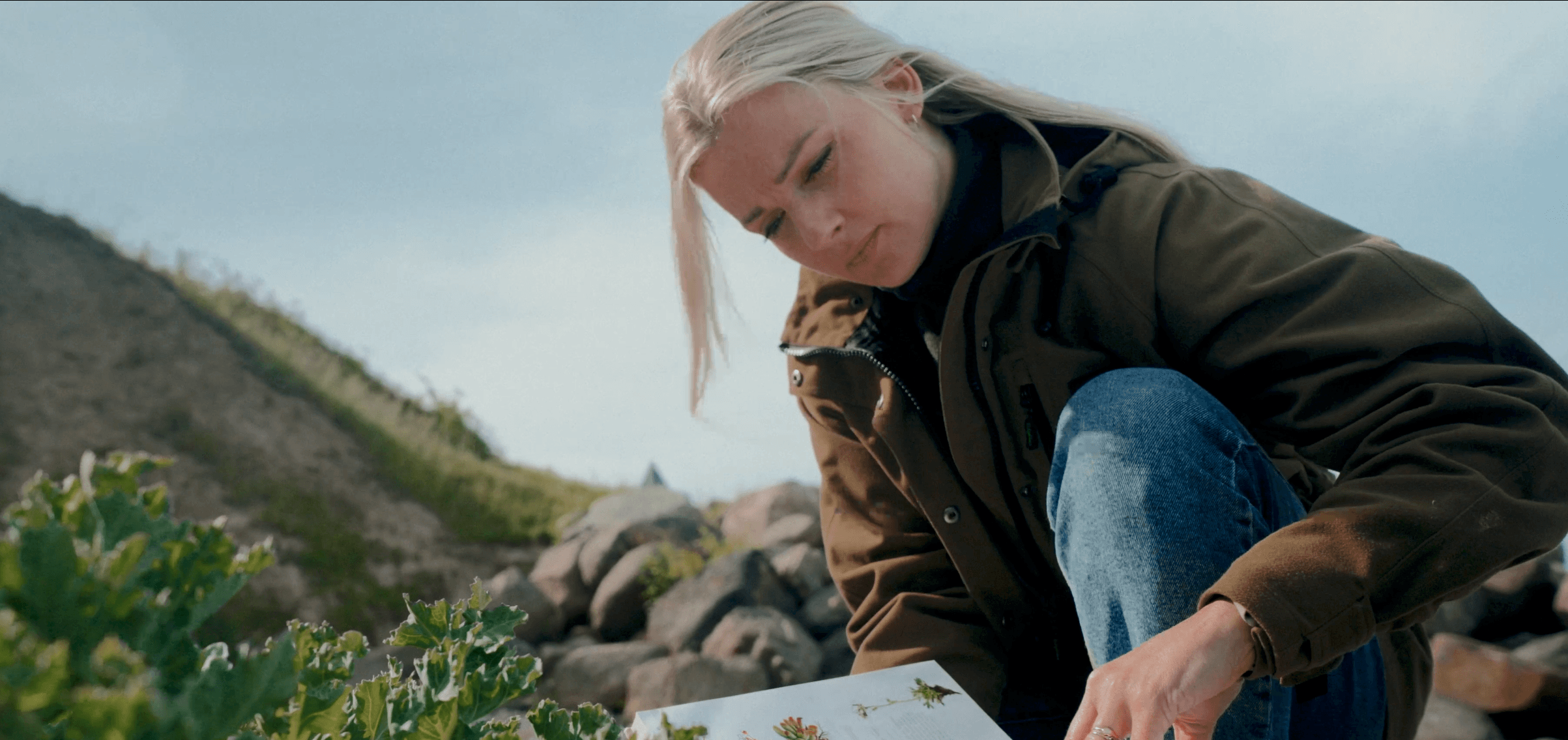 En jordbrugsteknolog studerende arbejder på et projekt udenfor, mens hun kigger i en fagbog.