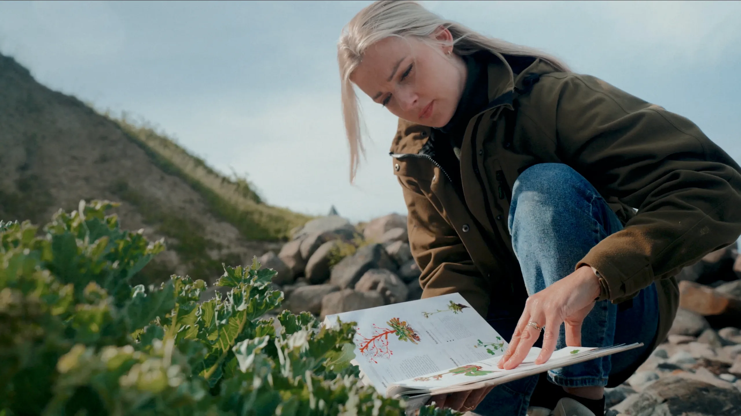 En jordbrugsteknolog studerende arbejder på et projekt udenfor, mens hun kigger i en fagbog.