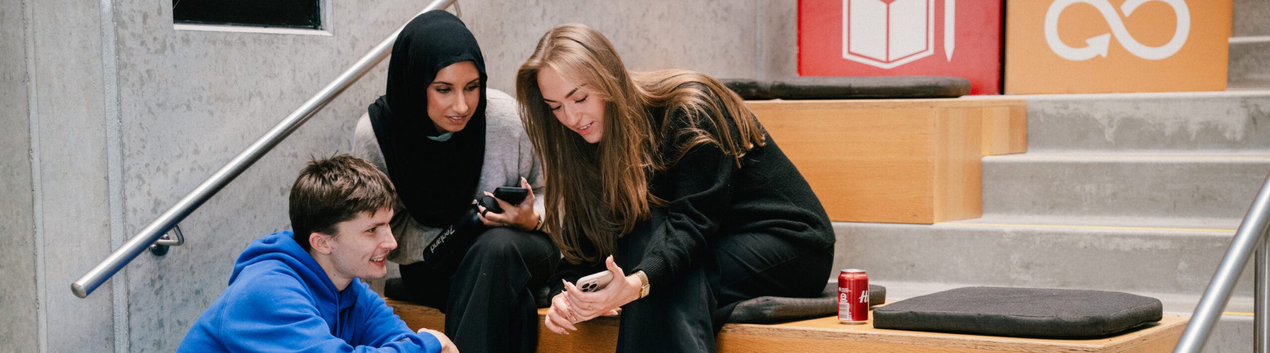 Tre studerende sidder sammen og snakker.